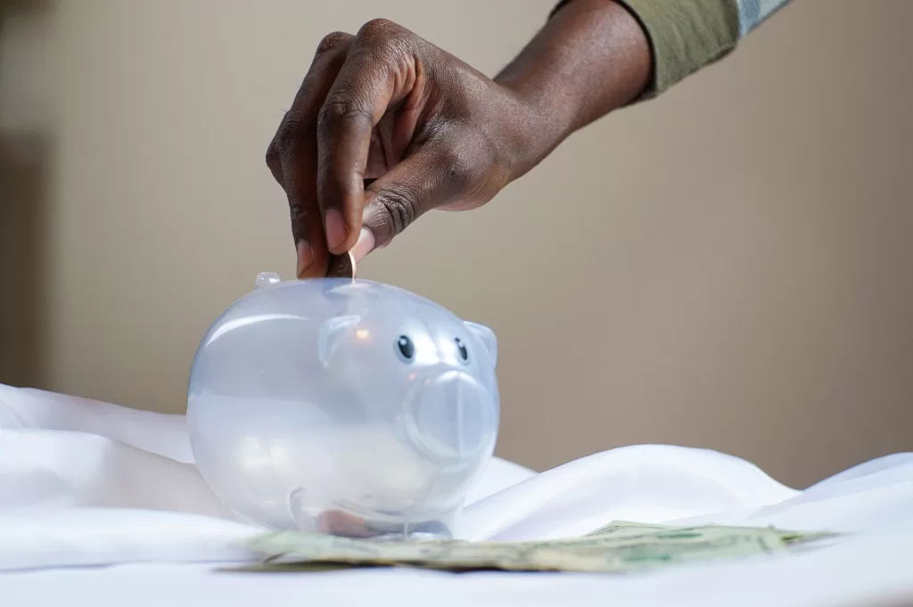Image of a person saving money in a piggy bank to denote the need to reduce transportation costs in logistics