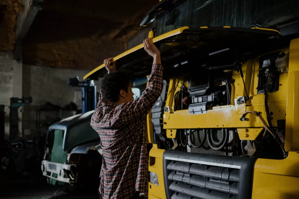 Image of a person fixing maintenance issues in a yellow colour truck.