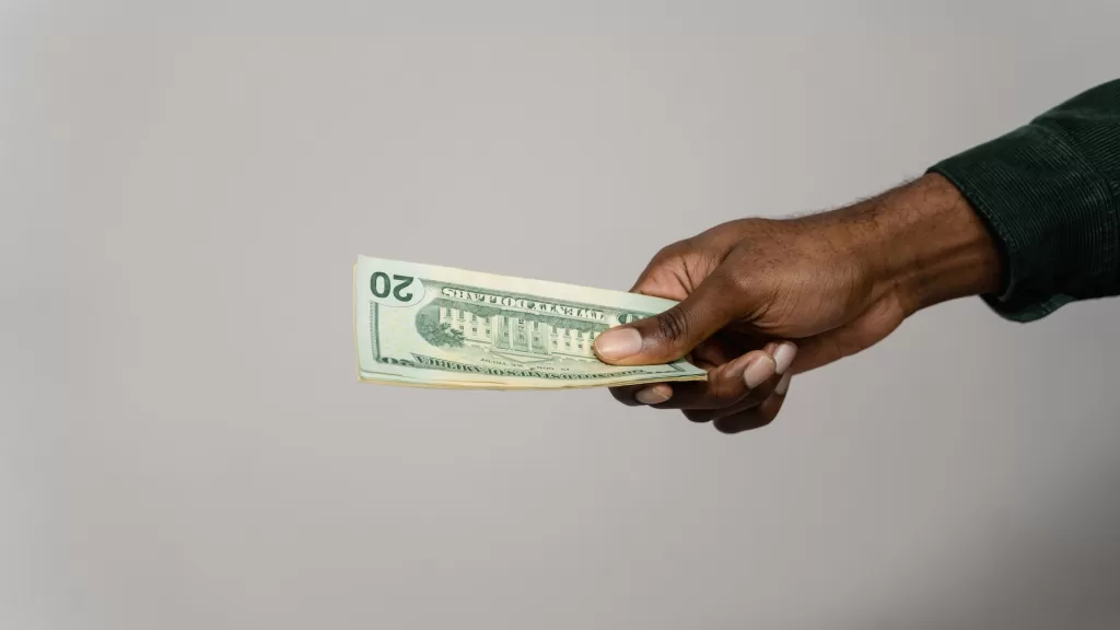 Image of a person handing out money to denote FASTag debit adjustment