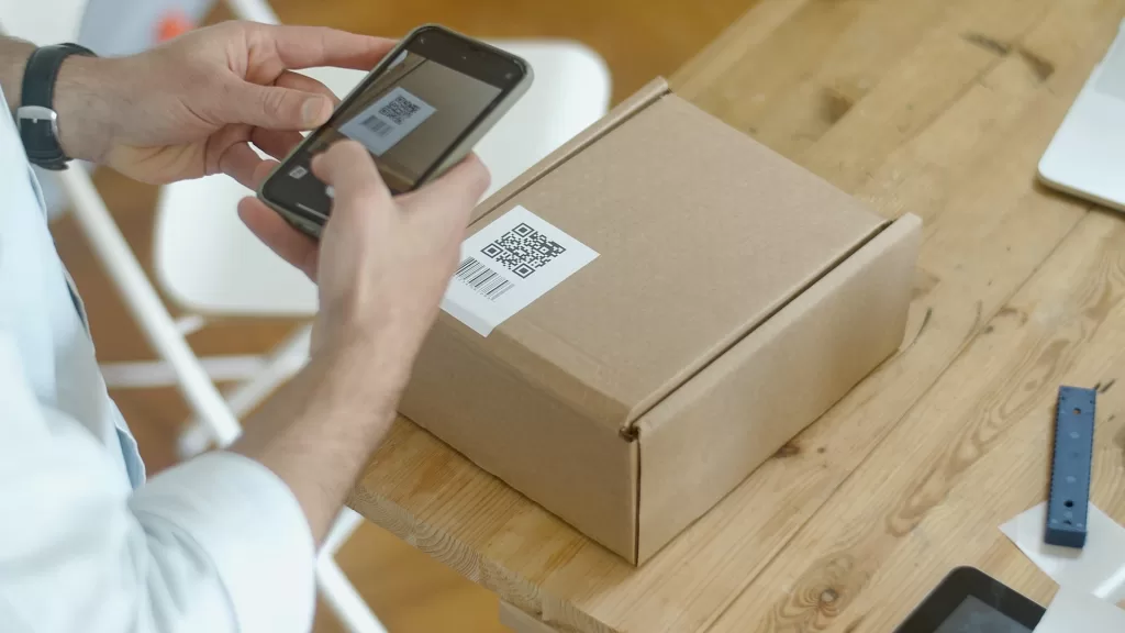 Image of a person making QR payment for a parcel to denote fintech and logistics